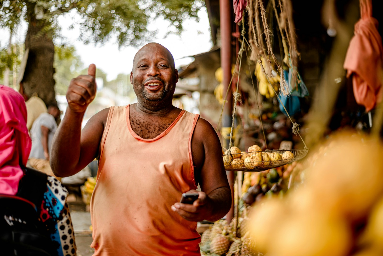 Lagos market vendor smiling with a phone in hand, confirming an order